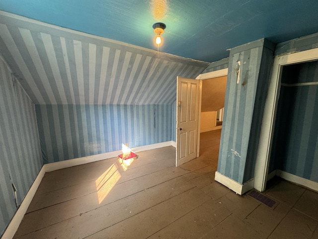 additional living space with wallpapered walls, lofted ceiling, and visible vents