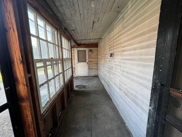 hall with wood ceiling and concrete flooring