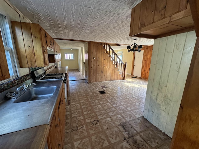 kitchen featuring wood walls, range with gas stovetop, tile patterned floors, an ornate ceiling, and a sink