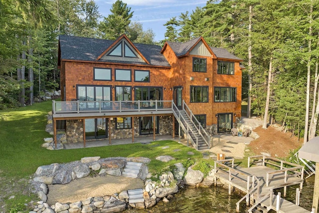 rear view of property featuring a wooden deck, a lawn, and a patio area