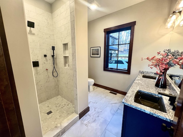 bathroom with vanity, a tile shower, and toilet