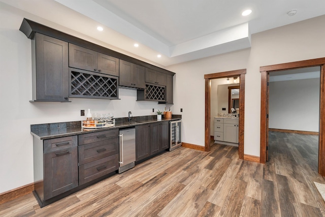 kitchen featuring sink, dark brown cabinets, dark stone countertops, and wine cooler