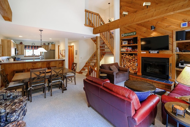 living area with a tile fireplace, recessed lighting, light carpet, a high ceiling, and stairway