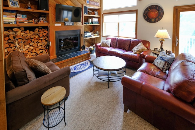 living area featuring built in features, a tile fireplace, a healthy amount of sunlight, and light colored carpet