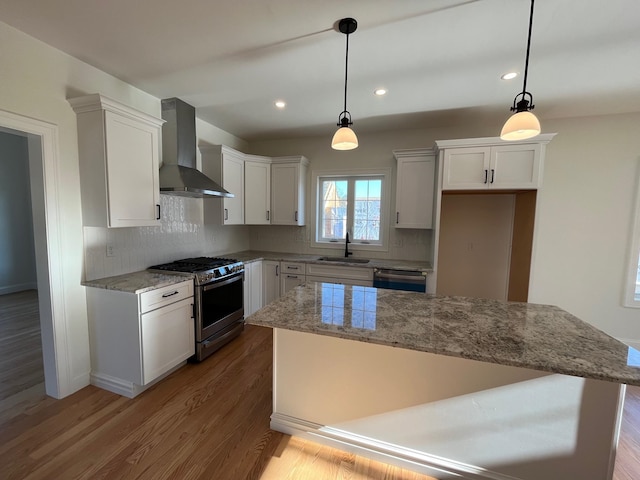 kitchen with pendant lighting, gas stove, backsplash, and wall chimney exhaust hood