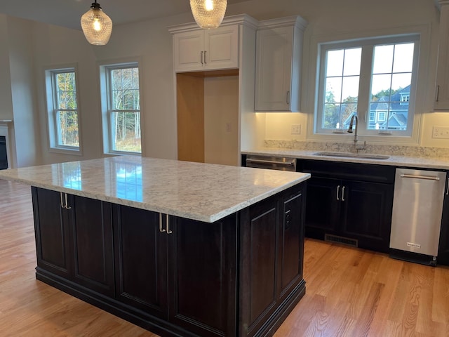 kitchen with light hardwood / wood-style floors, sink, stainless steel dishwasher, and white cabinets