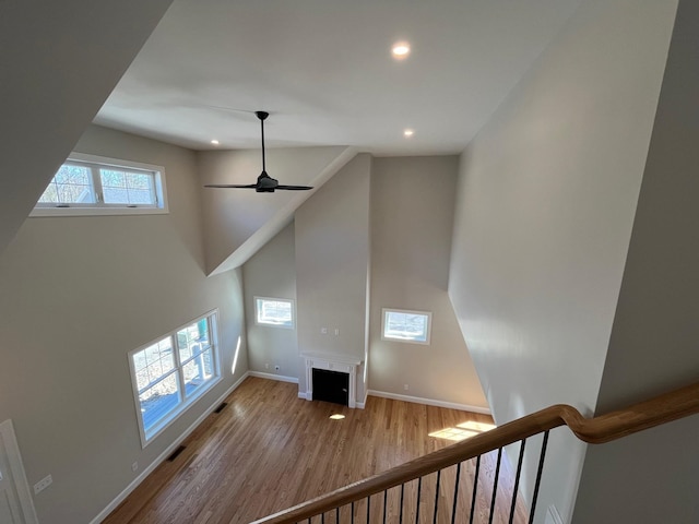 staircase featuring ceiling fan, wood-type flooring, and a towering ceiling