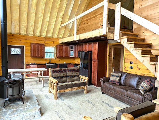 living room with wood walls, a towering ceiling, and a wood stove