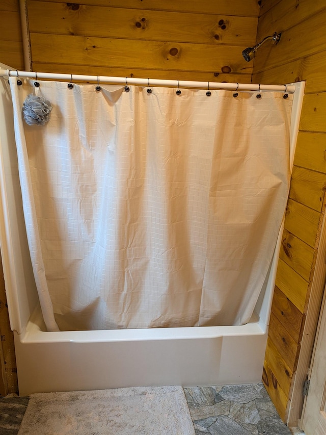 bathroom featuring shower / tub combo and wooden walls