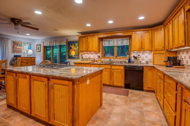 kitchen with sink, black dishwasher, light stone counters, stainless steel gas cooktop, and a kitchen island