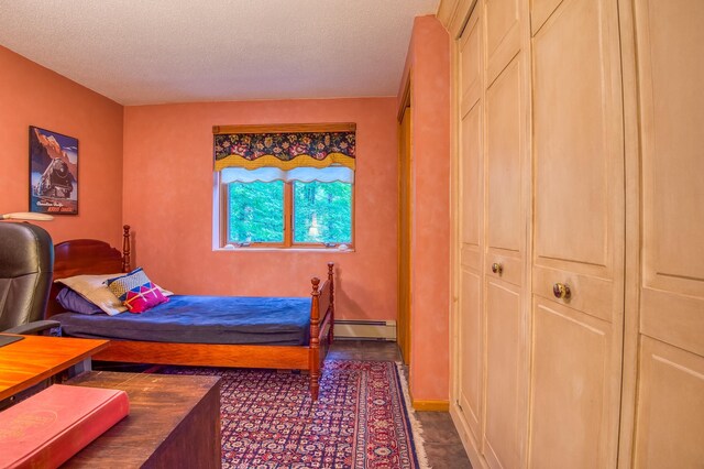 bedroom with a textured ceiling and a baseboard heating unit