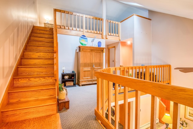 stairs with carpet and high vaulted ceiling