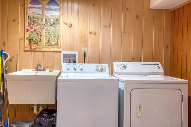 clothes washing area with independent washer and dryer, sink, and wood walls