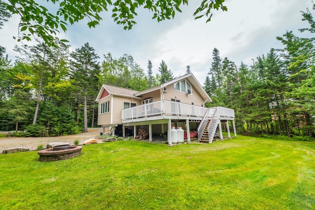 back of property featuring a wooden deck, a yard, and an outdoor fire pit