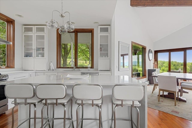 kitchen with white cabinets, light hardwood / wood-style floors, a kitchen bar, and sink