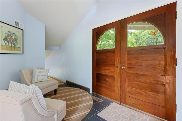 entrance foyer featuring lofted ceiling and dark tile patterned floors