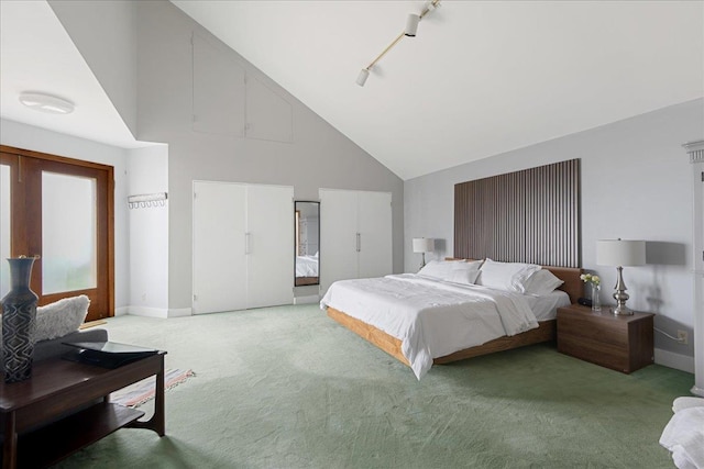 carpeted bedroom featuring high vaulted ceiling and rail lighting