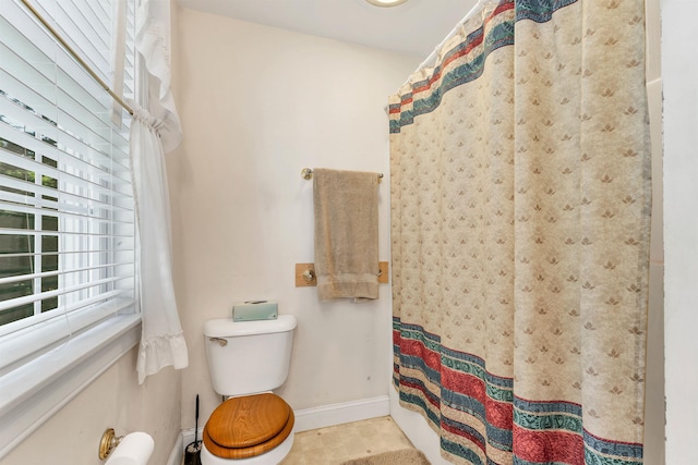 full bathroom featuring a shower with shower curtain, toilet, and baseboards