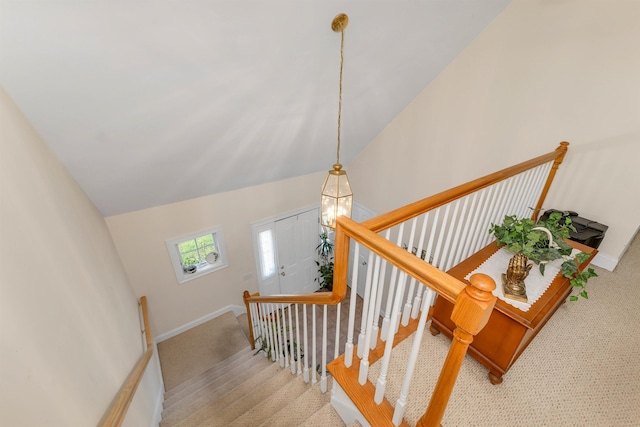 stairway with high vaulted ceiling, carpet, and baseboards