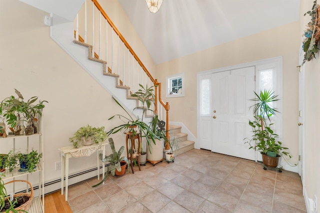 foyer entrance with lofted ceiling, a baseboard radiator, and stairway