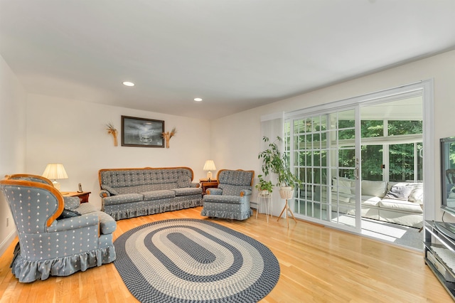 living area featuring a baseboard radiator, wood finished floors, and recessed lighting