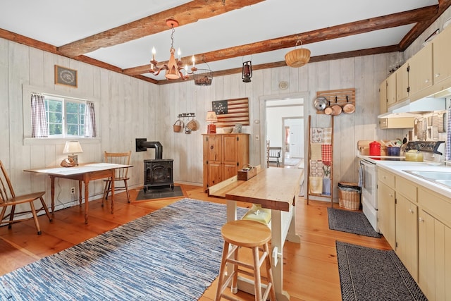 kitchen featuring decorative light fixtures, white electric stove, beamed ceiling, a wood stove, and light hardwood / wood-style floors