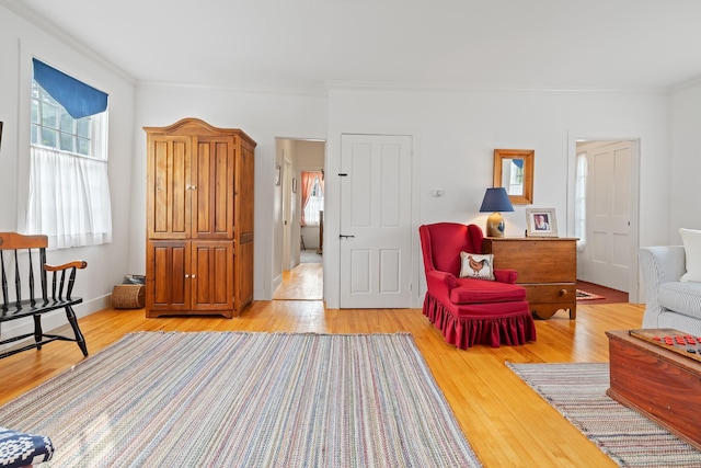 sitting room featuring ornamental molding and light wood-type flooring