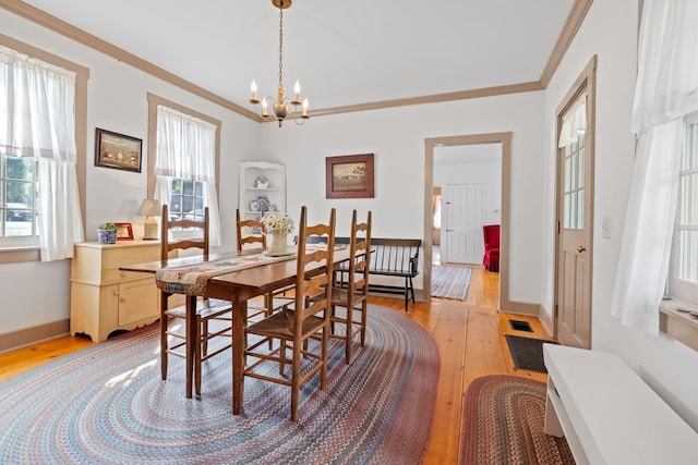 dining area featuring ornamental molding, an inviting chandelier, and light hardwood / wood-style flooring