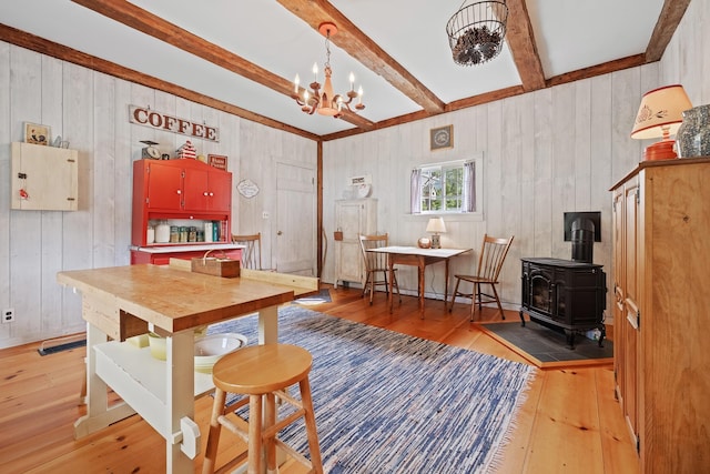 kitchen with light hardwood / wood-style flooring, a notable chandelier, a baseboard radiator, beamed ceiling, and a wood stove