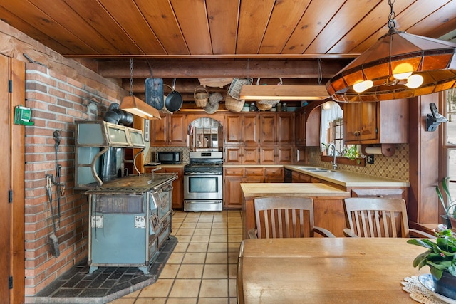 kitchen with black microwave, light tile patterned flooring, a sink, stainless steel gas range, and backsplash