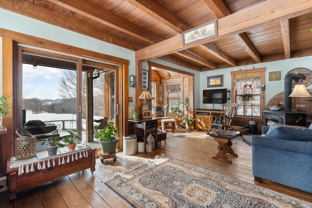 living room featuring wood ceiling, a wood stove, beamed ceiling, and hardwood / wood-style flooring