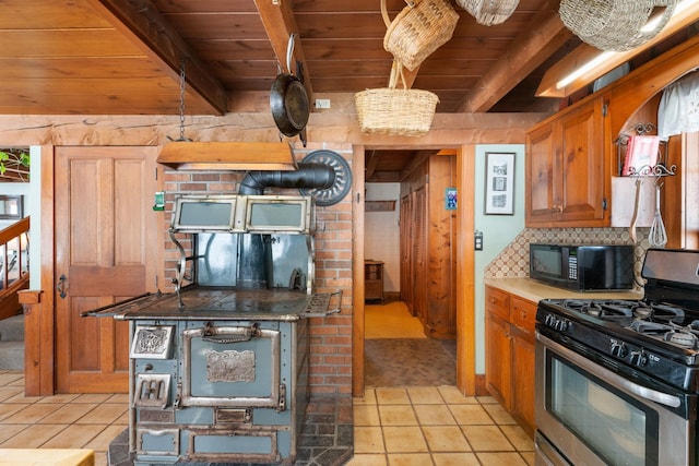 kitchen featuring tasteful backsplash, stainless steel range with gas stovetop, brown cabinets, black microwave, and beam ceiling