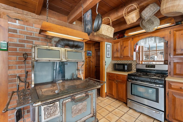 kitchen with black microwave, wood ceiling, stainless steel gas range, beam ceiling, and decorative backsplash