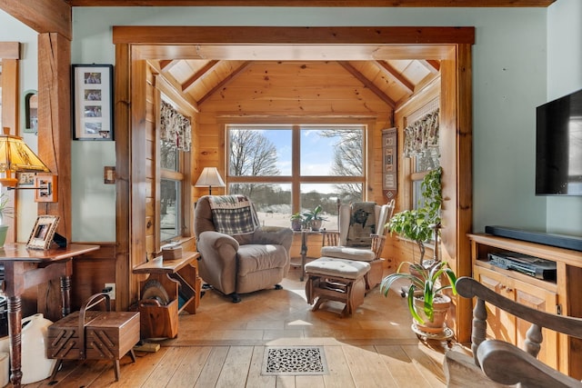 sitting room featuring wooden walls, wood ceiling, lofted ceiling with beams, and hardwood / wood-style floors