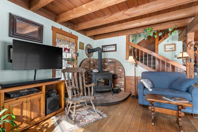 living area with wooden ceiling, hardwood / wood-style flooring, a wood stove, stairs, and beam ceiling