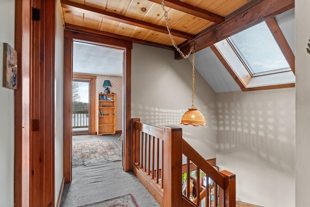 hall with carpet, wooden ceiling, vaulted ceiling with skylight, and an upstairs landing