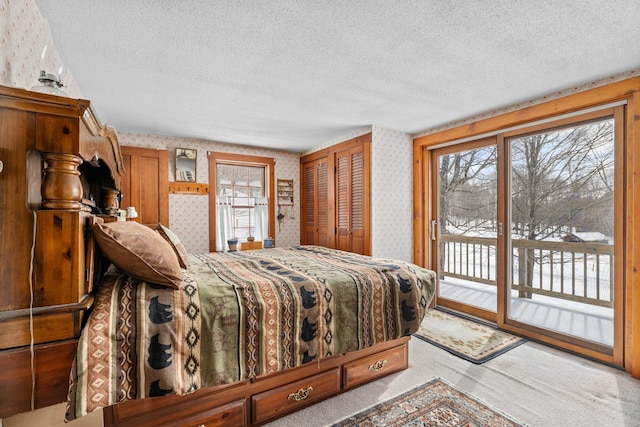 carpeted bedroom featuring access to outside, a textured ceiling, and wallpapered walls