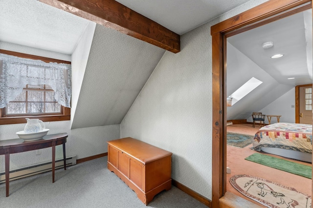 bonus room featuring a baseboard heating unit, vaulted ceiling with skylight, light carpet, and baseboards