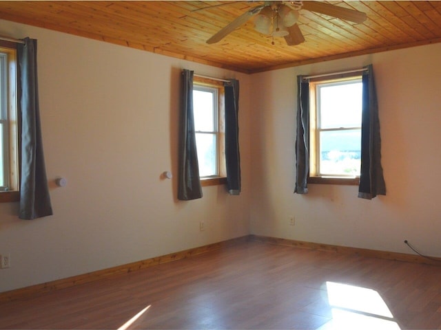 empty room with wood ceiling, plenty of natural light, hardwood / wood-style floors, and ceiling fan