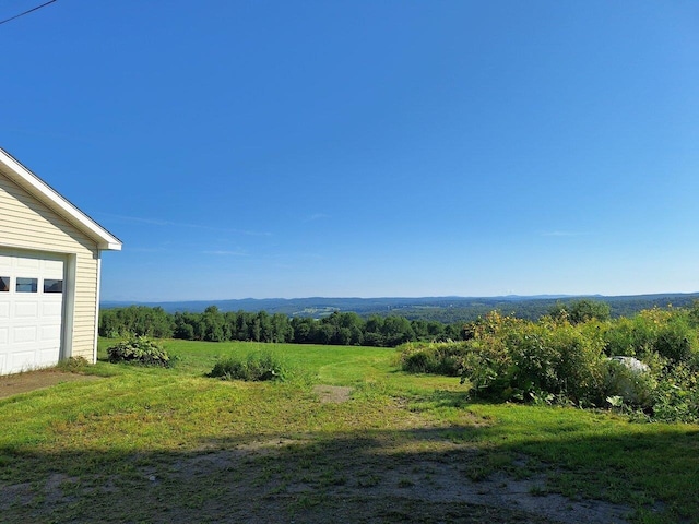 view of yard featuring a rural view and a garage