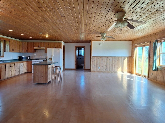 kitchen with white appliances, a kitchen breakfast bar, a kitchen island, ceiling fan, and wooden ceiling