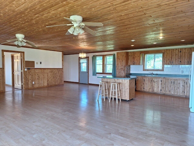 kitchen with a breakfast bar area, light wood-type flooring, ceiling fan, backsplash, and wooden ceiling