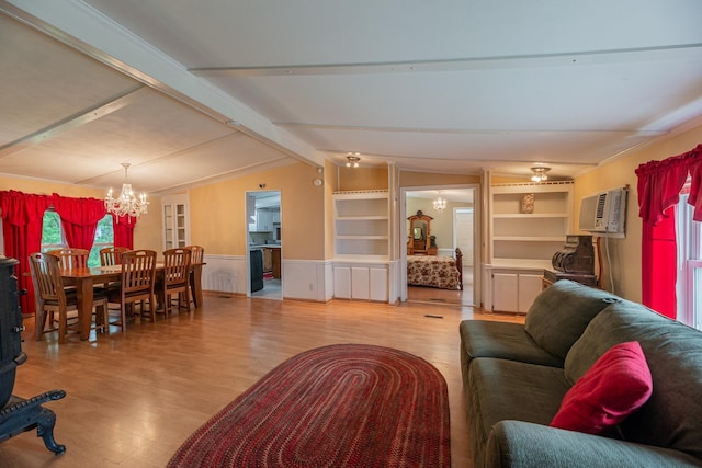 living area featuring a notable chandelier, wood finished floors, vaulted ceiling with beams, and a wall mounted AC