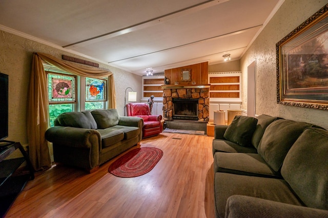 living area featuring built in features, wood finished floors, ornamental molding, a fireplace, and a textured wall