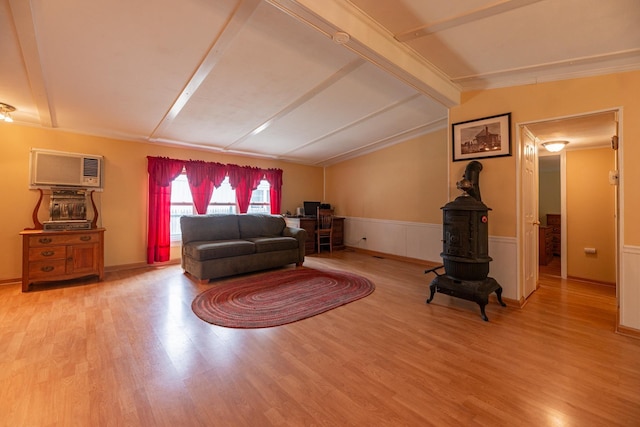 living area with wood finished floors, vaulted ceiling with beams, and a wall unit AC