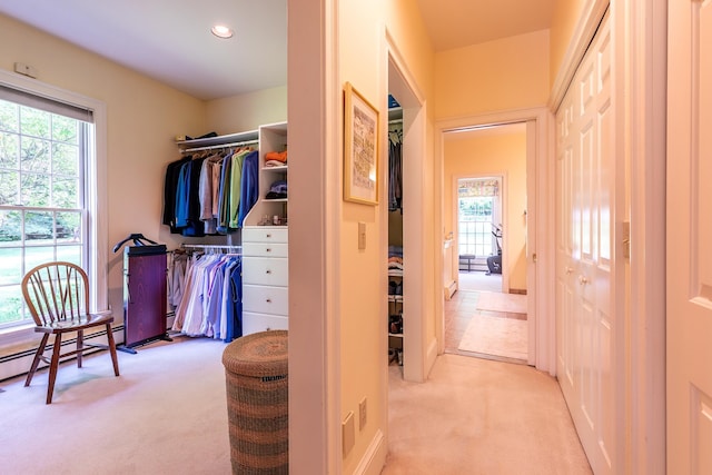 corridor with a healthy amount of sunlight, light colored carpet, and baseboard heating