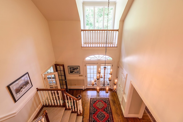 entrance foyer featuring a baseboard heating unit, a high ceiling, stairway, dark wood-style floors, and an inviting chandelier