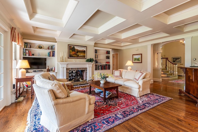 living area with arched walkways, decorative columns, a brick fireplace, wood finished floors, and coffered ceiling