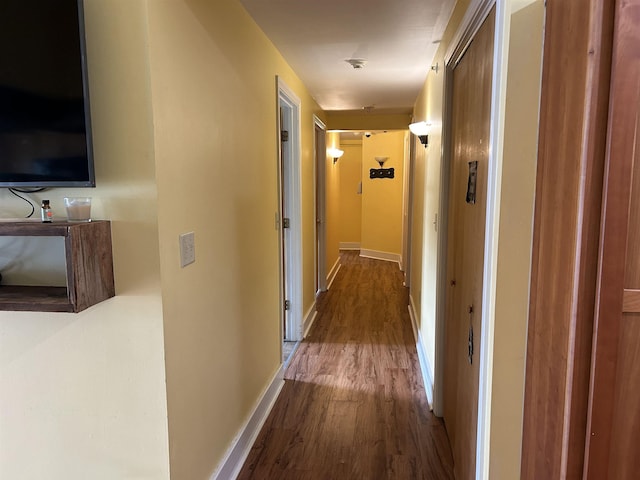 corridor with baseboards and wood finished floors