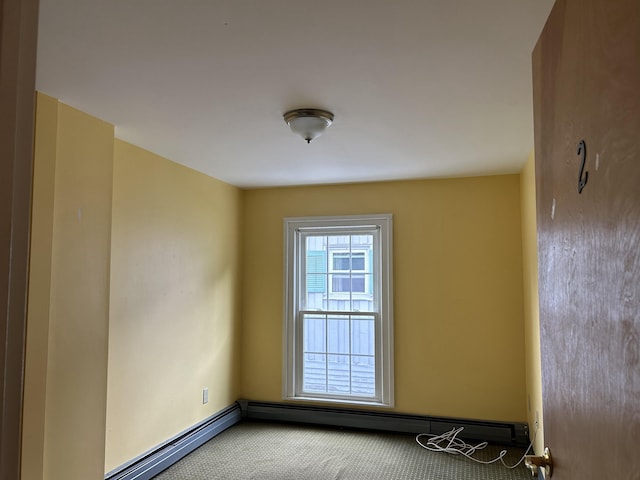 spare room featuring a baseboard heating unit, baseboards, and carpet floors